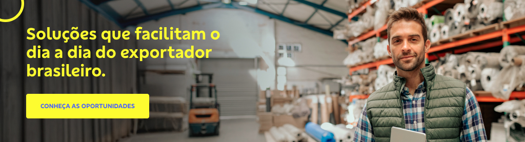 Homem jovem de barba rala e cabelo castanho, vestindo camisa xadrez e colete verde, segurando um tablet em um galpão industrial com prateleiras cheias de rolos de tecido. Ao fundo, empilhadeira e estrutura metálica do armazém. Texto à esquerda: "Soluções que facilitam o dia a dia do exportador brasileiro." Botão amarelo com o texto: "CONHEÇA AS OPORTUNIDADES". 