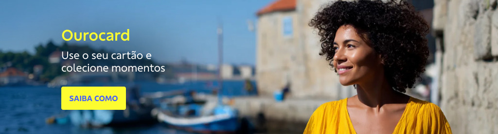 Mulher negra usando um vestido amarelo observa sorridente uma paisagem à beira-mar com barcos e construções históricas ao fundo, sob céu azul. À esquerda da imagem, o texto diz: Ourocard. Use o seu cartão e colecione momentosLogo abaixo, há um botão amarelo com o texto em azul: SAIBA COMO 